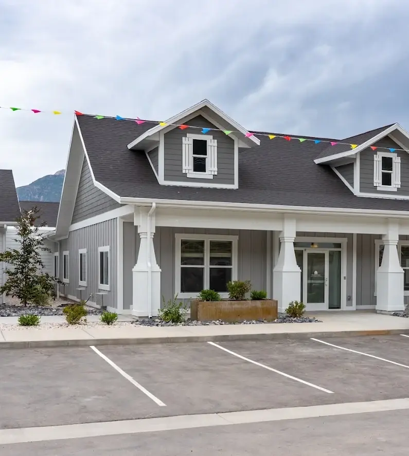 One of the Hearthstone buildings, with a covered front porch and the Wasatch mountains behind it