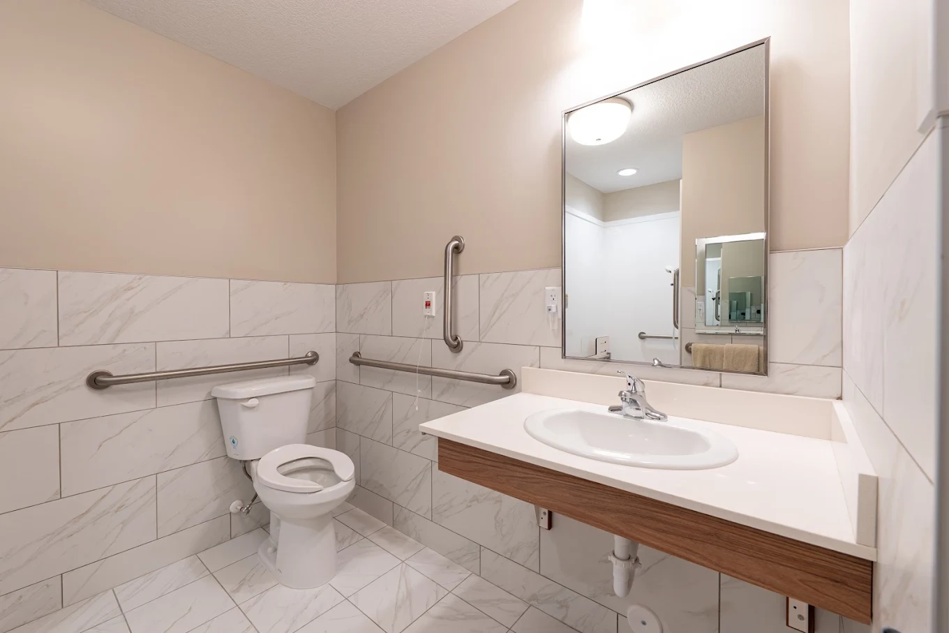 An accessible private bathroom with grab bars and an emergency pull cord