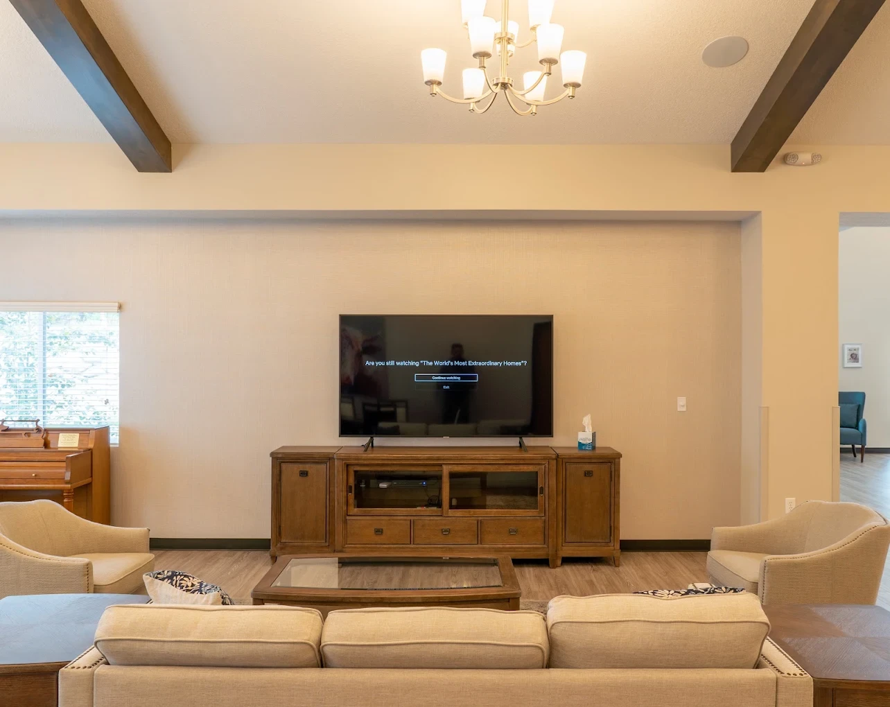 The TV lounge with sofas, armchairs, and a piano